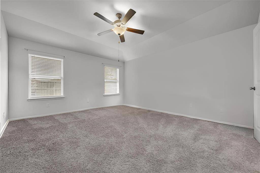 The Grand Sized Primary Bedroom Features High Ceilings, a Lighted Ceiling Fan, and Double Door Access to the Primary Bath.
