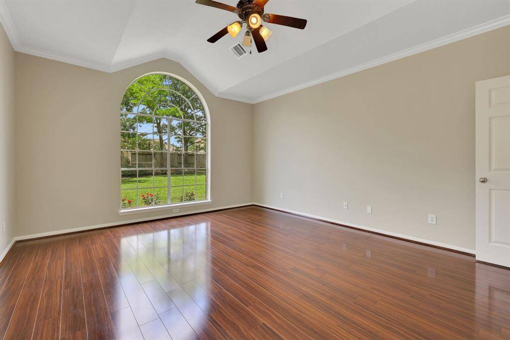 Retreat to your primary suite featuring wood floors, high ceilings, abundant natural light, and ample space for a luxurious king-sized bedroom set.