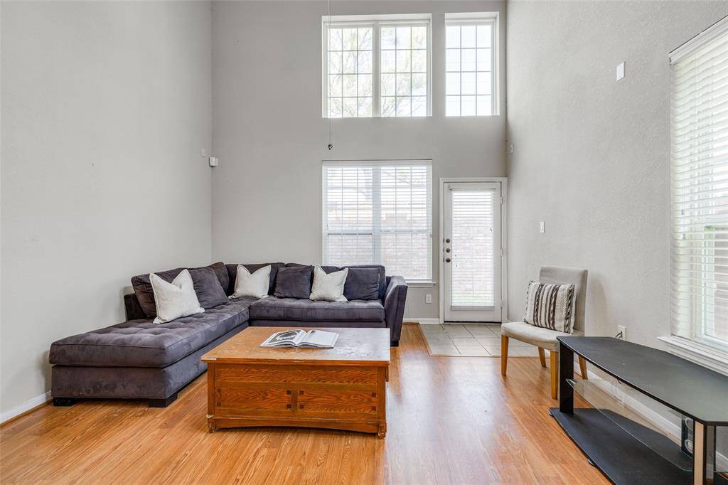 Living Room with wood floors, high ceilings, 2 inch blinds for privacy. Back door leading out to small back yard.