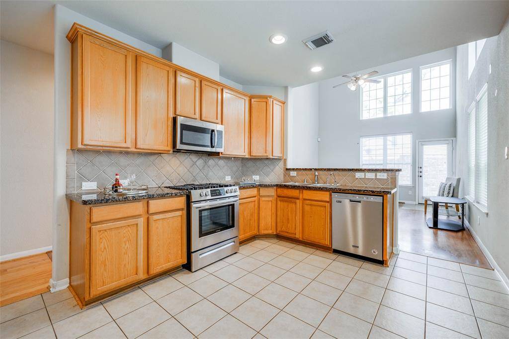 Large kitchen with lots of cabinets, gas cooker, SS dishwasher, granite counter tops & tile back splash