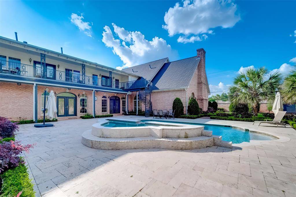Enjoy luxurious outdoor living with a stunning pool, elegant balcony, and charming house backdrop.