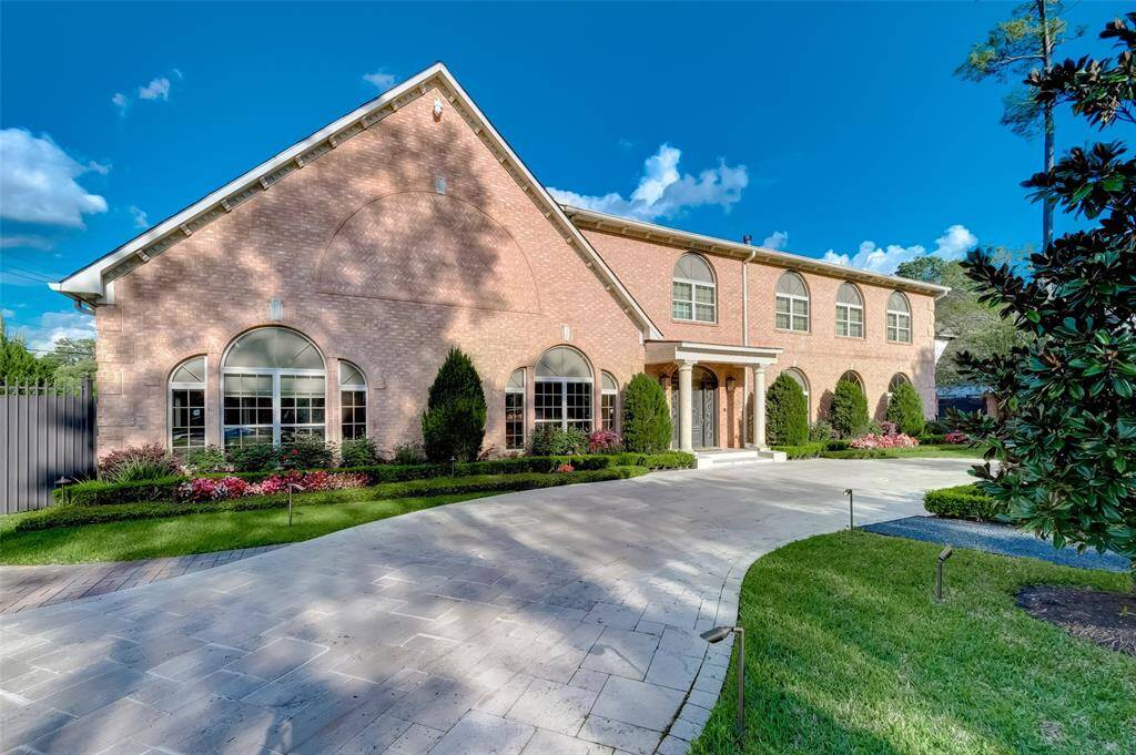Elegant brick home with stunning curb appeal, featuring a beautifully landscaped driveway and classic architectural details.