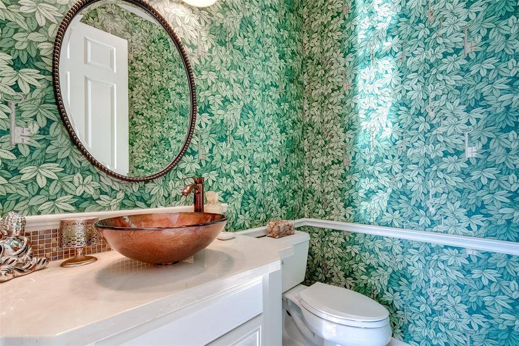 Charming powder room featuring lush, leafy wallpaper, a stylish copper vessel sink, and warm accents for a welcoming touch.