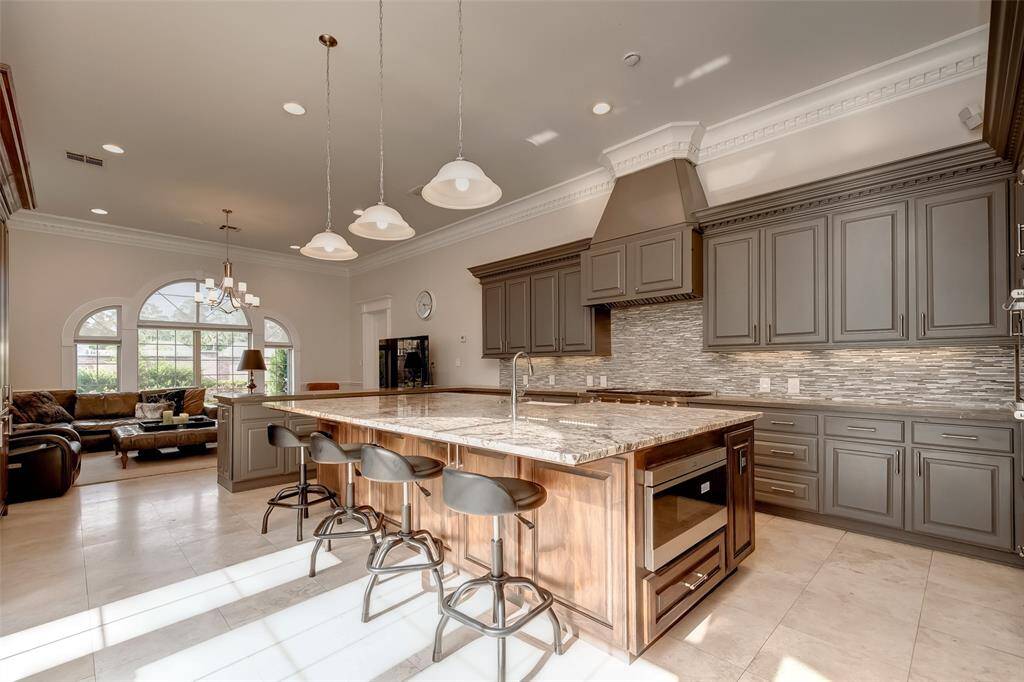 Explore this elegant kitchen featuring modern cabinetry, a spacious island with seating, and abundant natural light perfect for culinary creations and gatherings.