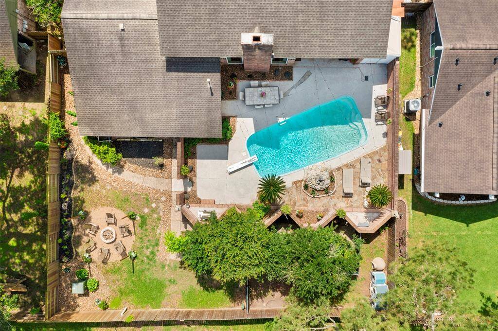 Overhead view of the back yard. Notice the brick wall around the pool area, fire pit to the left and directly behind the pool is an enclosed area perfect for securing your pups or planting a fabulous garden!