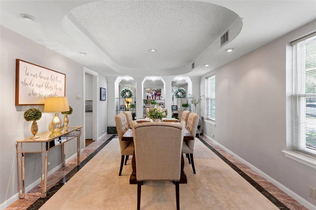The formal dining room features marble flooring, tray ceiling and built in shelving.