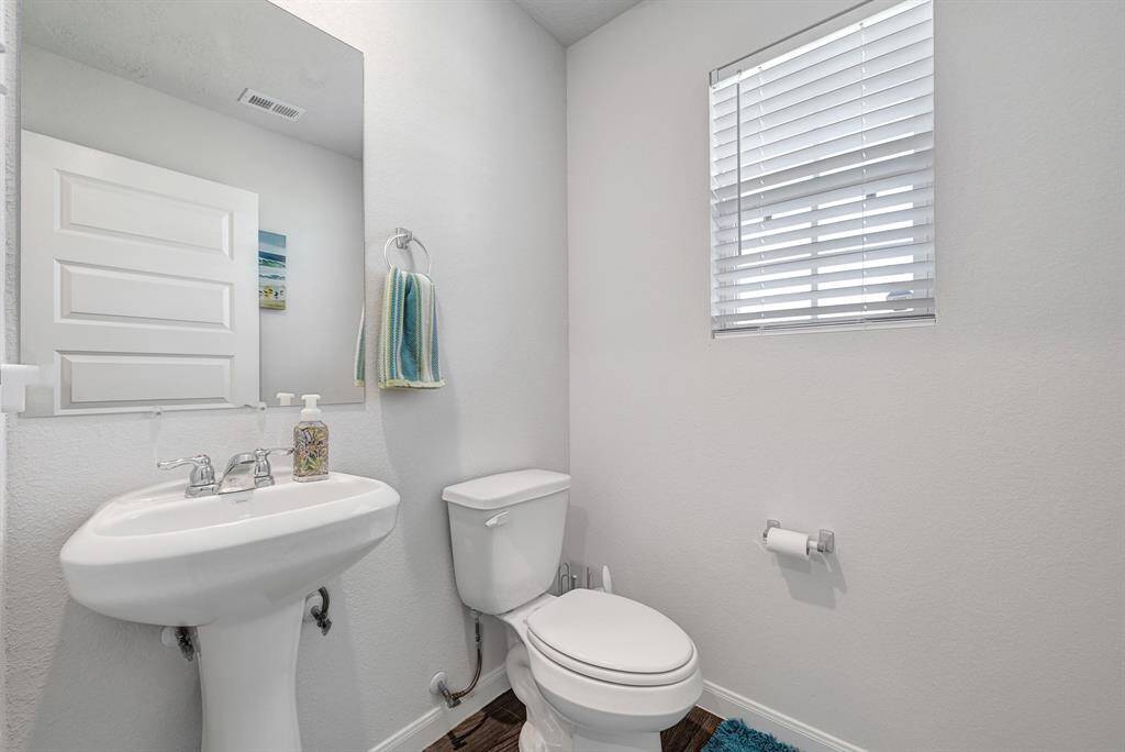 The first floor half bathroom features a clean, minimalist design with a pedestal sink & modern fixtures.