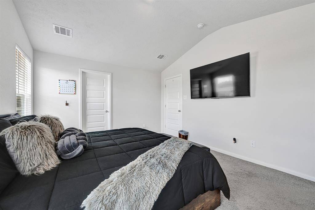 Secondary bedroom features a modern design with neutral tones and plush carpeting. It has ample natural light from the windows and clean lines with a minimalistic style.