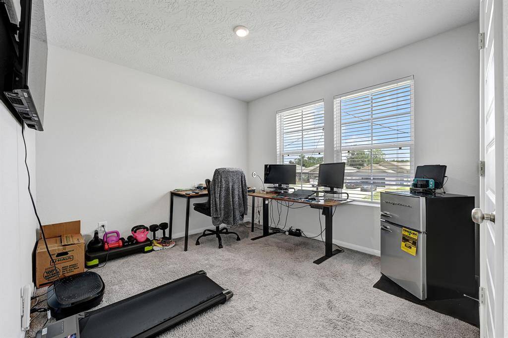 This bright, carpeted room is ideal for a home office or workout space, featuring two large windows for natural lighting.
