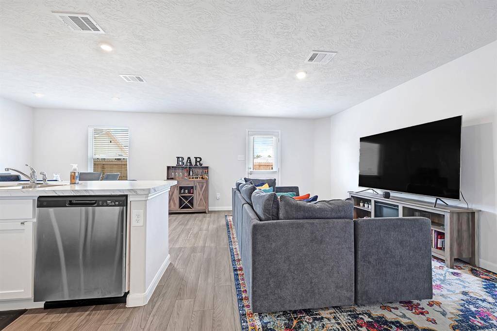 The home offers a bright, open-concept living area featuring a modern kitchen with a stainless steel dishwasher and island seating. The space flows into a cozy living room, perfect for entertaining.