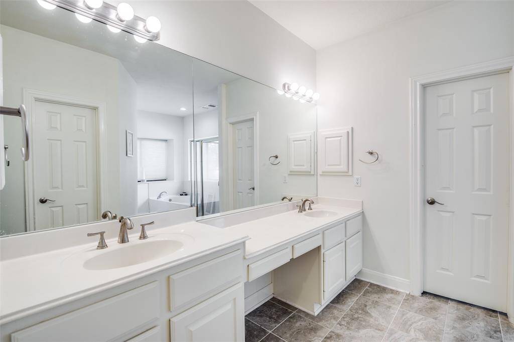 A view of the double sink vanity in the spacious primary bedroom en-suite bathroom. Directly behind the vanity is a large soaking tub with a separate shower offering a beautiful view of the backyard oasis.