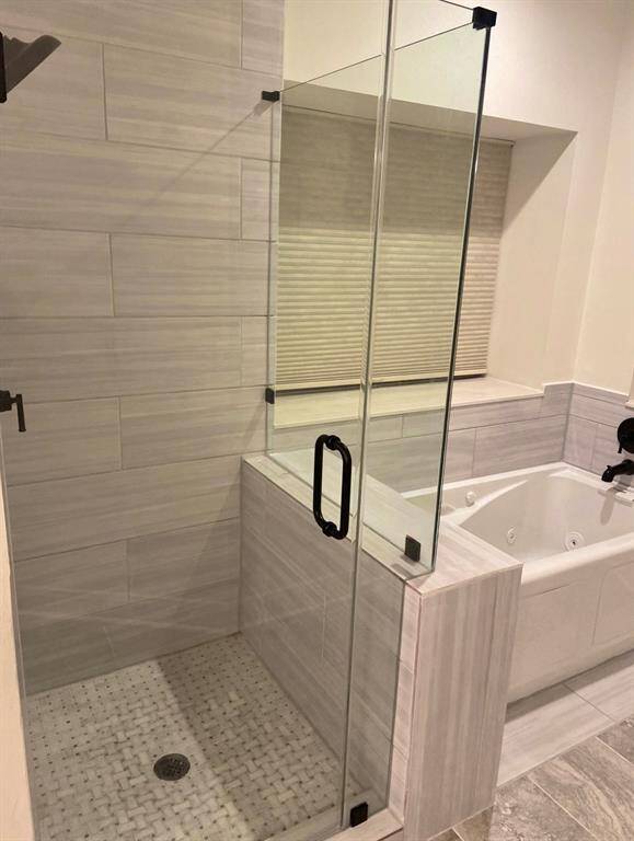 Here is another view of the primary bedroom en-suite bathroom's large soaking tub and separate shower. Open the blinds for a beautiful view of the backyard oasis while you relax and unwind!
