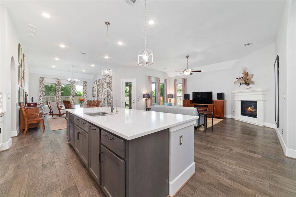 A large quartz island with rich, contrasting cabinetry and a deep sink serves as the focal point, offering abundant prep space and casual seating.