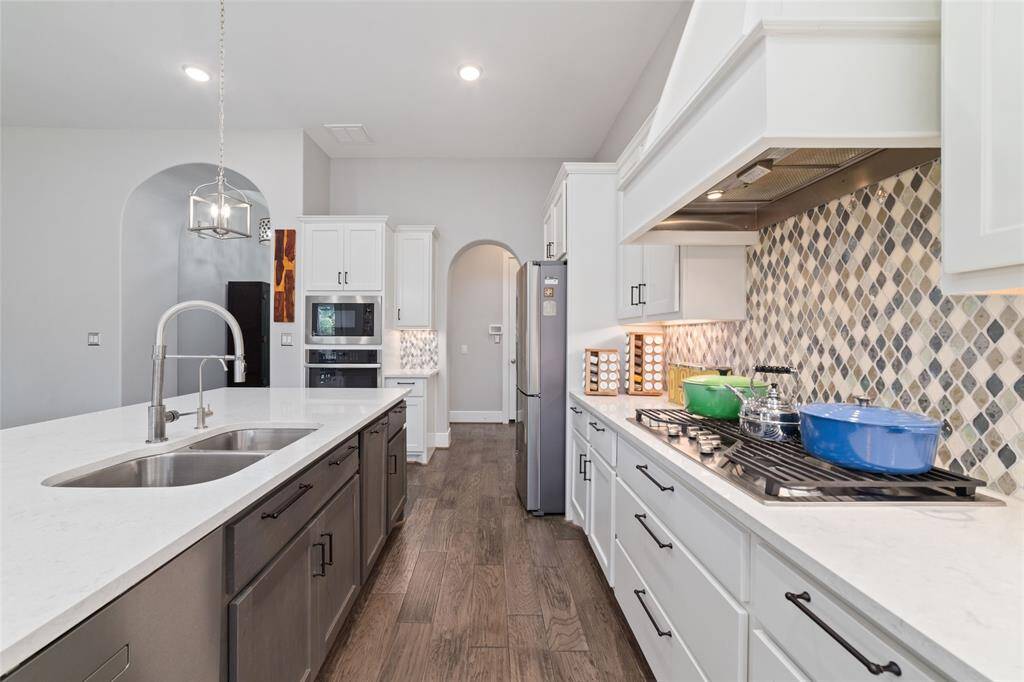 A closer view of the kitchen's cooktop and elegant backsplash facing the grand island, perfect for food prepping as well as a great place for conversations.