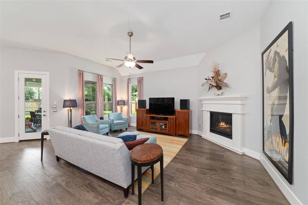 The living room features a cozy gas fireplace with an elegant mantle and built-in surround, creating a warm and welcoming atmosphere. Expansive windows throughout flood the space with natural light, while the neutral palette and stylish finishes enhance the home’s bright, airy feel.