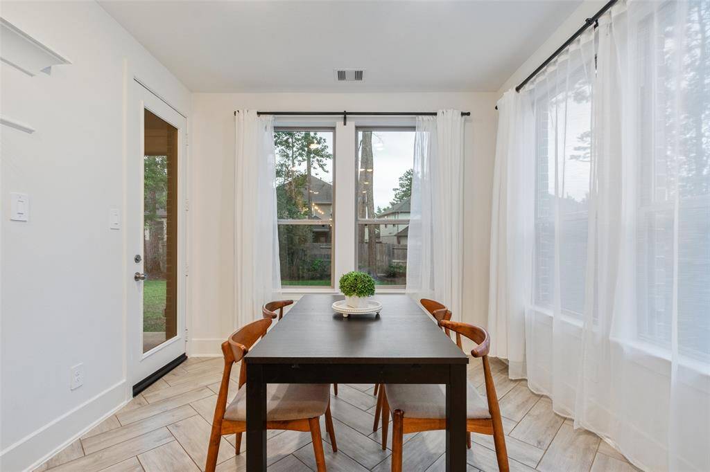Bright Breakfast area with large windows, sheer curtains, and a glass door leading outside. The windows allow for natural light.