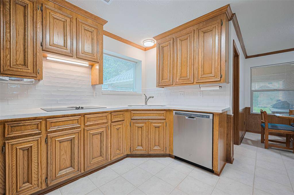 The kitchen includes a stainless steel divided sink with a disposal and an overhead light for added visibility. A Whirlpool stainless steel dishwasher offers convenience and blends seamlessly with the other updated appliances.