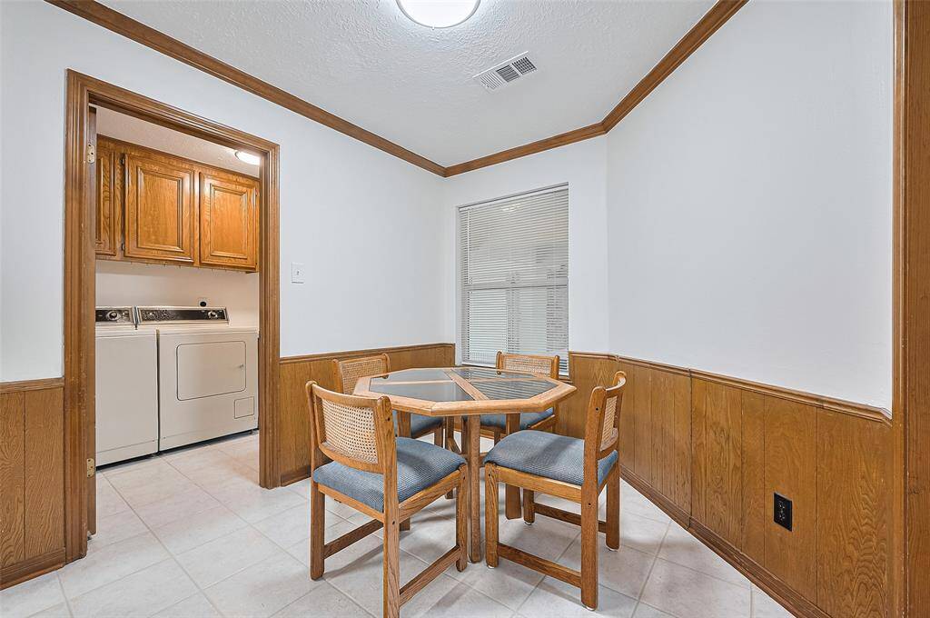 The breakfast room includes a window overlooking the covered patio that leads to the garage and backyard—an ideal space for outdoor cooking and year-round enjoyment. To the left, an open doorway leads to the indoor utility room for added convenience.