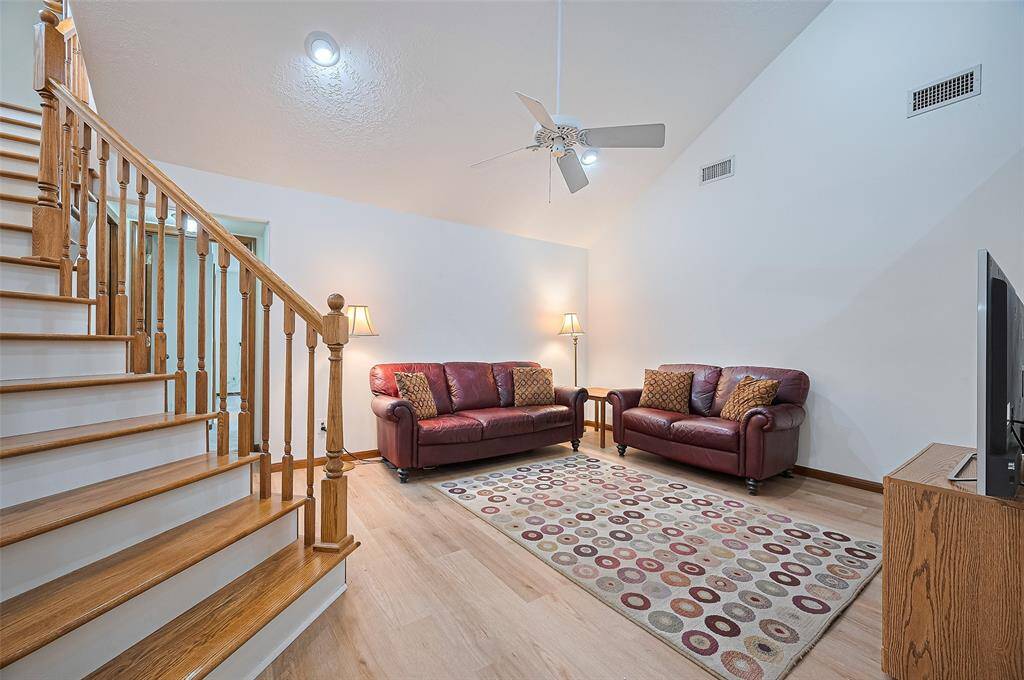 The family room, measuring 15' x 13', offers plenty of space for relaxation. In 2002, the owners extended the home to include a 1st-floor guest suite with a full bathroom, a half-bathroom, and a 2nd-floor gameroom. The doorway to the guest suite is visible through the staircase spindles on the far wall of the family room.