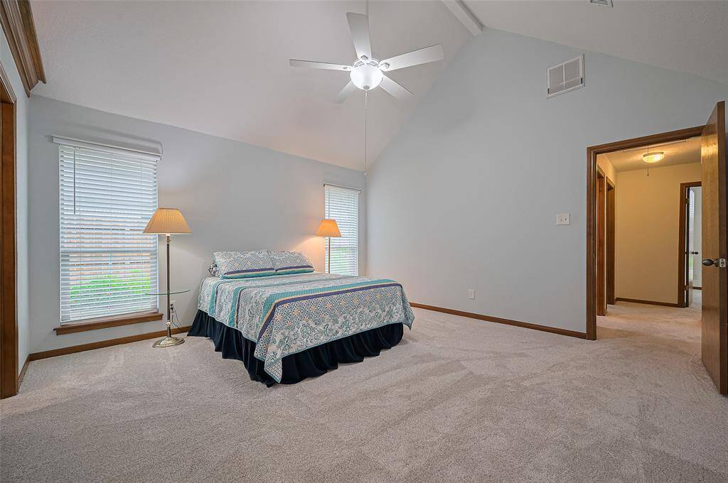 At the end of the hallway is Bedroom #1 – the Owner's Suite, measuring 14'8" x 14'3". It features a vaulted ceiling and two floor-to-ceiling windows that overlook the side yard, filling the room with natural light. This spacious room offers ample wall space for displaying and arranging furniture, making it very versatile for various layout options.