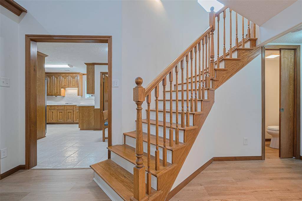 Returning to the staircase in the family room, in 2002, the owners expanded the home. They removed a wet bar and creating a convenient half-bathroom in its place. The half-bath features a pocket door for space-saving efficiency. Behind the family room is a 4th bedroom with its own ensuite bath, offering privacy and comfort. Upstairs, you'll find a large gameroom, complete with a sizable storage closet and expansive, floored attic space for even more storage options.