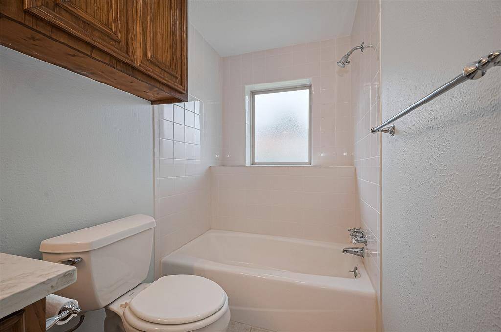Bath #3 features a combination tub-shower with tiled walls that extend all the way from the ceiling to the tub ledge, creating a seamless, clean look. A frosted window allows for privacy while letting in natural light. The tiled shower ledge provides convenient access to bath accessories, enhancing both functionality and ease of use.
