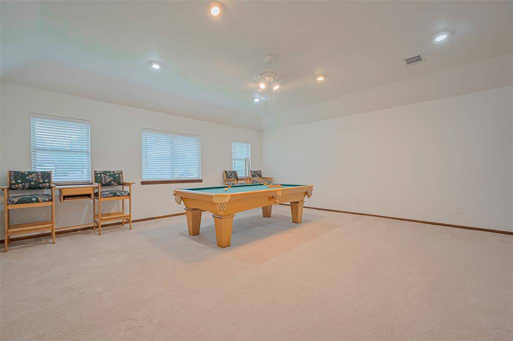 The ONLY room upstairs is the gameroom, measuring 19'8" x 19'7". Windows with 2-inch blinds overlook the backyard, allowing natural light to fill the space. A ceiling fan and recessed LED lighting add comfort and brightness. This versatile room offers endless possibilities—whether as a gameroom, second living area, man-cave, home office, homeschool classroom, children's playroom, hobby room, or sewing room. The options are limitless!