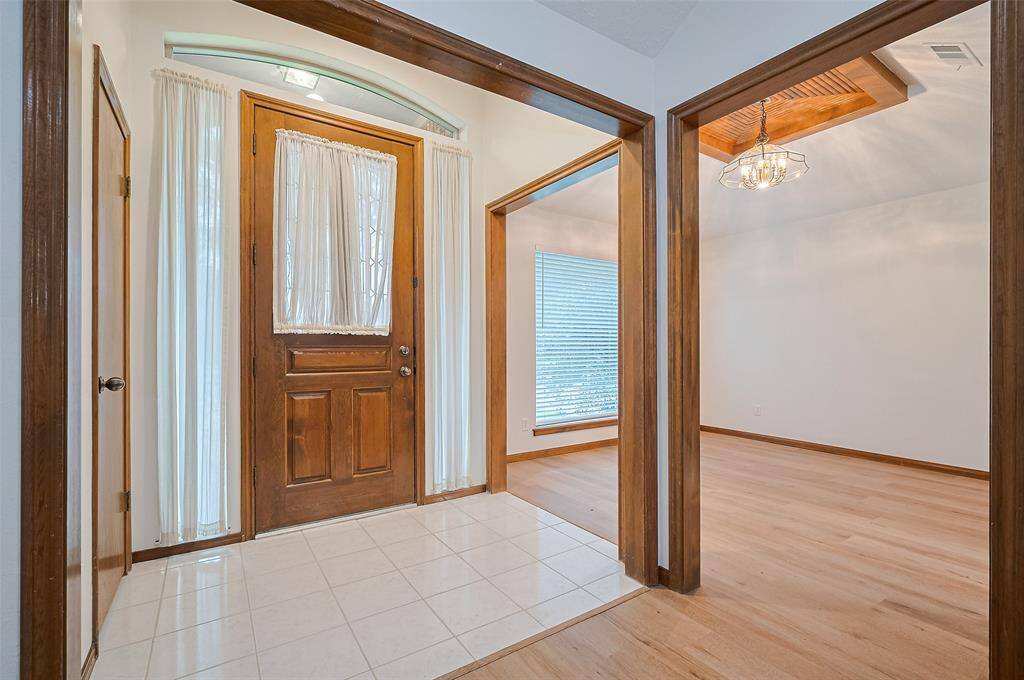 The elegant front door opens to a tile-floor foyer with high ceilings and a convenient coat closet. To the right, a wide opening leads to the formal dining room—perfect for gatherings—while straight ahead, the spacious living room with a cozy fireplace invites you to relax and unwind.