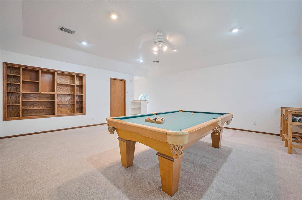 A door in the gameroom leads to a large storage closet, extending behind bookshelves for added convenience. Beyond the closet is a massive floored attic space, offering plenty of room for additional storage. This home is equipped with two HVAC systems: the 2002 addition (Gameroom and Bedroom #4) shares one system, while the remainder of the house is served by the other. Both systems feature digital programmable thermostats for efficient temperature control.