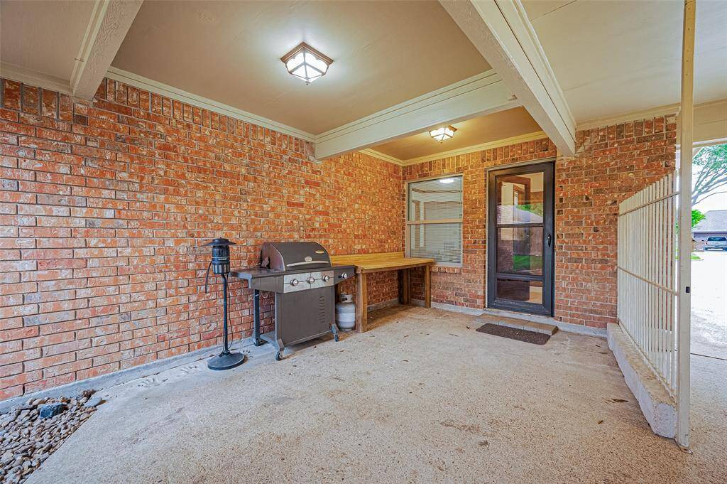 The breezeway connecting the house and garage has been expanded to create a covered patio area, complete with a glass storm door. This space is perfect for outdoor cooking and entertaining. A wrought iron fence along the driveway provides added security, allowing the backyard to be fully enclosed. This feature ensures that children and pets can play safely in the backyard, offering peace of mind while enjoying the outdoors.