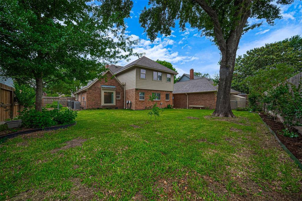 The backyard offers a clear view of the home's brick exterior, with the upper portion of the 2002 extension finished in durable Hardie board siding. Situated on a spacious 10,625 sq ft lot, there's plenty of room for children and pets to run and play. A fenced garden area on one side of the home provides a dedicated space for growing vegetables, herbs, or flowers.