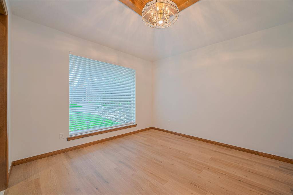 The 11' x 10'11" formal dining room features a modified mansard ceiling that rises to a decorative wood accent for the chandelier, adding architectural charm. A large front-facing window with 2-inch blinds fills the room with natural light. There's ample space for a dining table and wall space perfect for displaying a China hutch or serving buffet.