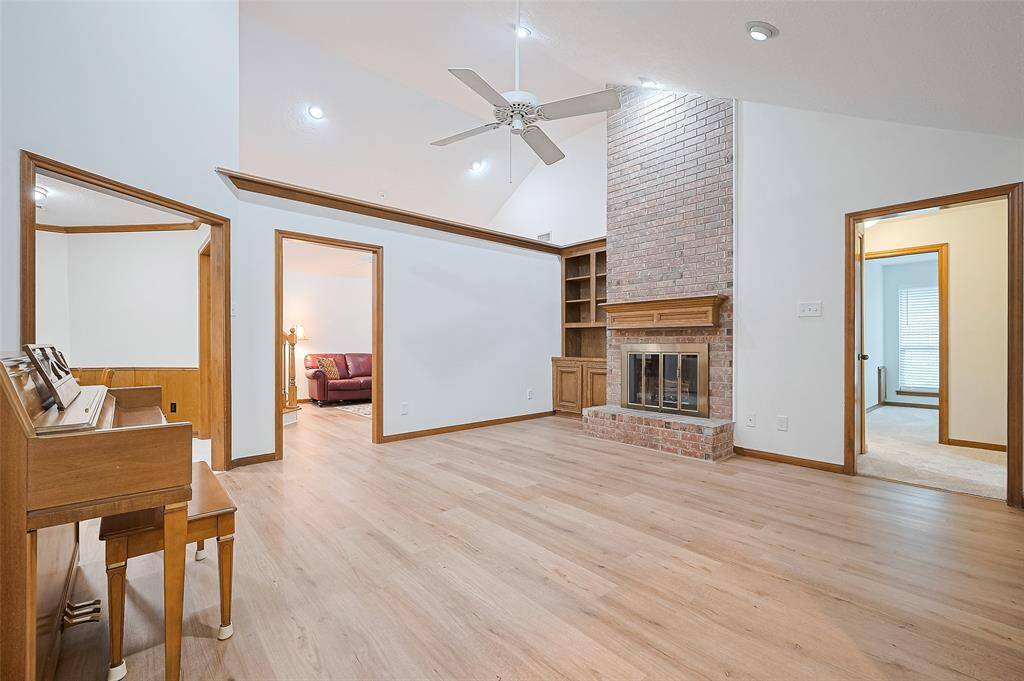 The floor-to-ceiling brick fireplace serves as the stunning focal point of the room, featuring a wood mantle, brick hearth, and glass doors. It is easy to imagine holiday stockings hanging from the mantle with eager children gathered around on Christmas morning. To the left, a built-in bookshelf provides space for books or cherished décor.