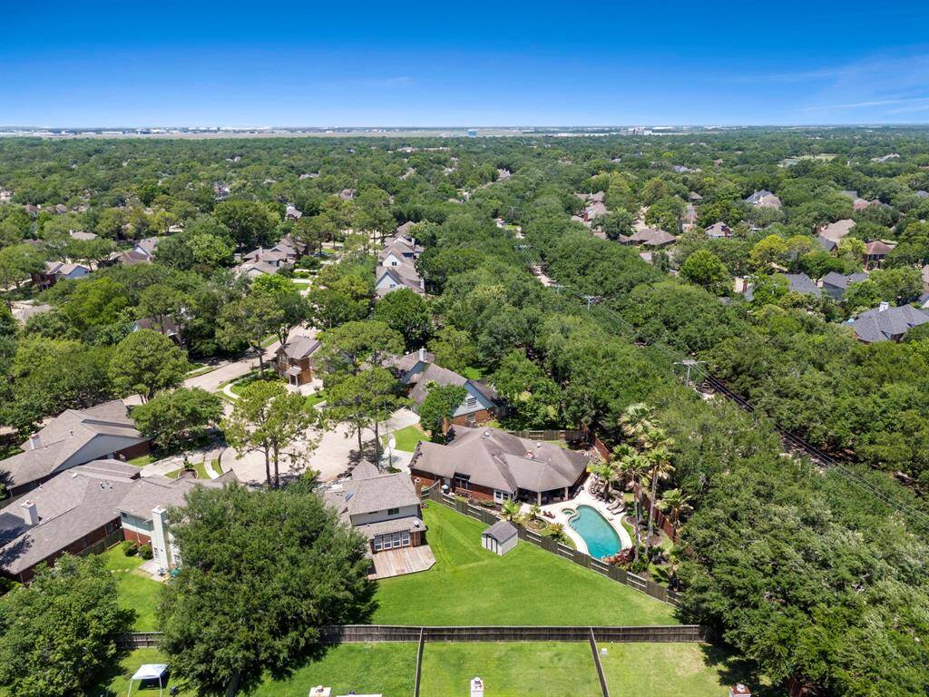 This aerial photo showcases a lush, green suburban neighborhood with tree-lined streets.
