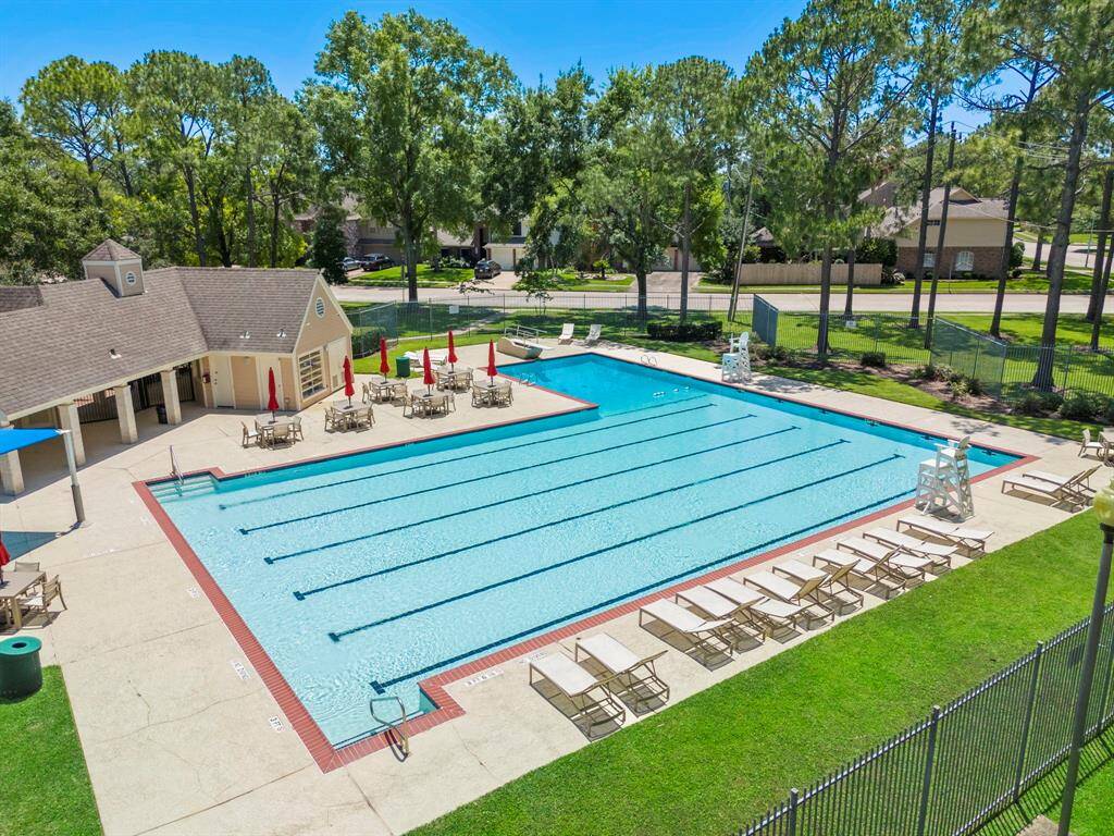 Bay Glen offers a spacious community pool area with lap lanes, surrounded by lounge chairs and shaded tables. It's adjacent to a clubhouse, set in a lush, green neighborhood.