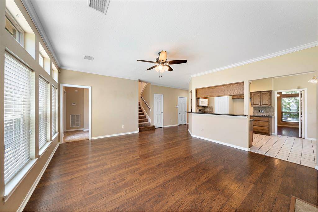This spacious living area features hardwood floors, abundant natural light from large windows, and an open layout that seamlessly connects to the kitchen.