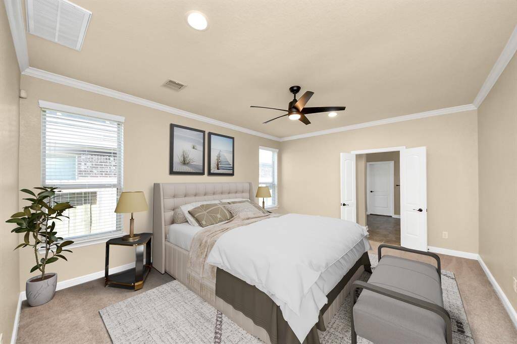 This photo showcases a spacious, well-lit bedroom with light-color walls and carpet. It features a ceiling fan, large windows, and double doors leading to an adjoining room. The room is elegantly furnished with a bed, nightstands, and decor.VIRTUAL IMAGE