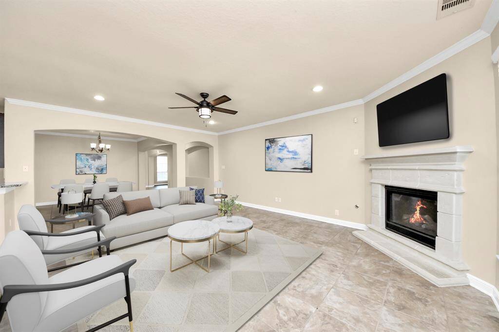 This spacious living area features an open floor plan with a cozy fireplace, neutral tones, and modern furnishings. The adjacent dining space and ample natural light create a welcoming atmosphere, perfect for entertaining or relaxing. VIRTUAL IMAGE