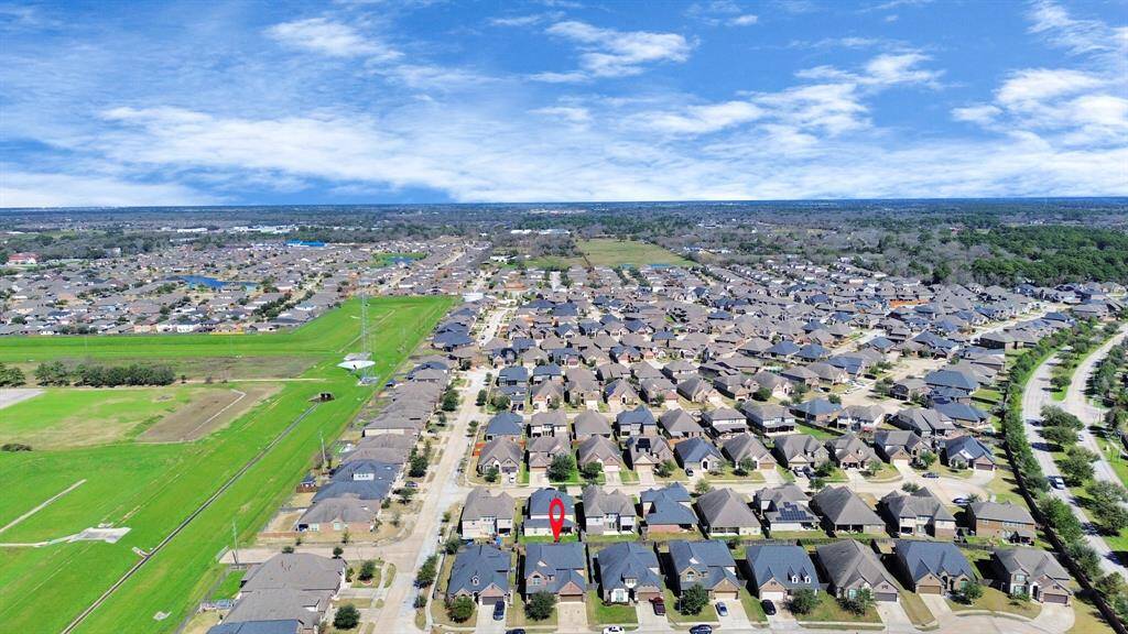 This aerial photo showcases a residential neighborhood adjacent to a sprawling, lush golf course with multiple water features and tree-lined fairways, offering scenic views and a tranquil setting.