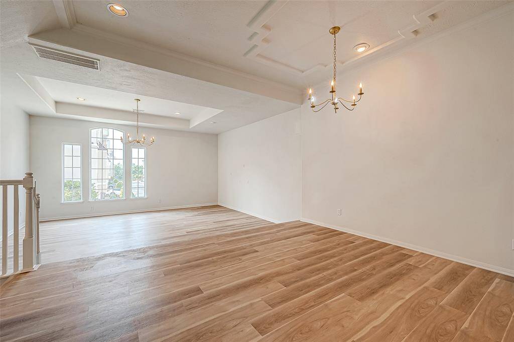 Spacious open-concept living and dining area with elegant chandeliers and abundant natural light.