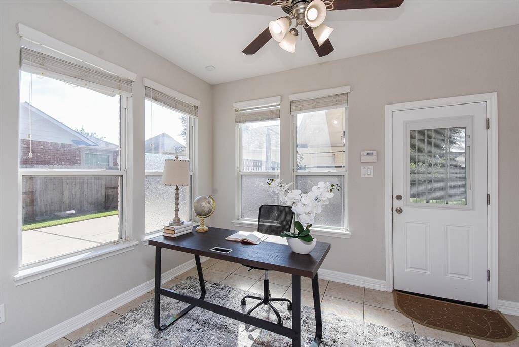 Bright from multiple windows, the office offers a calm and focused atmosphere. A  glass-paned door opens to the backyard, blending indoor productivity with outdoor accessibility.