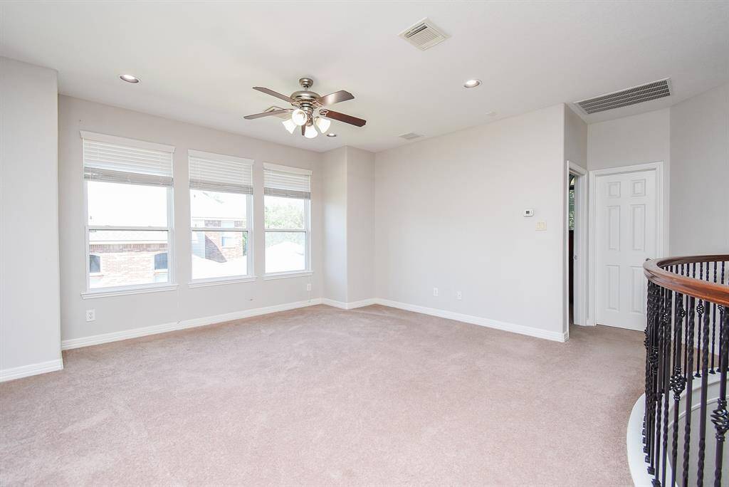 This versatile upstairs space, illuminated by large windows and recessed lighting, offers room for gaming or lounging - a flexible extension of the home’s living areas.