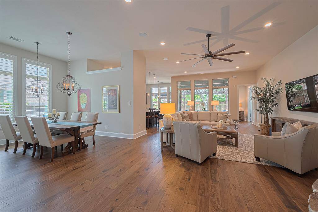 To the left, a formal dining room offers an elegant space for entertaining, while the family room draws you in straight ahead. Toward the back left, the stunning kitchen with an adjoining breakfast area completes the open layout. Standout features include rich wood flooring, a soft neutral color scheme, impressive 8-inch baseboards, and a wall of windows that frame the covered back patio—filling the home with natural light and highlighting one of its most desirable features.