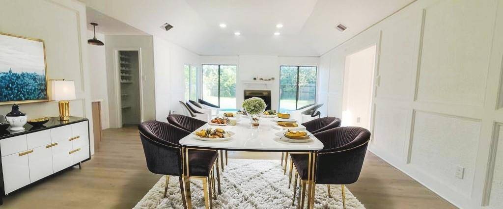 This bright, open-concept dining and living area features a sleek, cozy fireplace, large windows offering abundant natural light, and elegant wood vinyl planks flooring, and a wet bar. Virtually staged