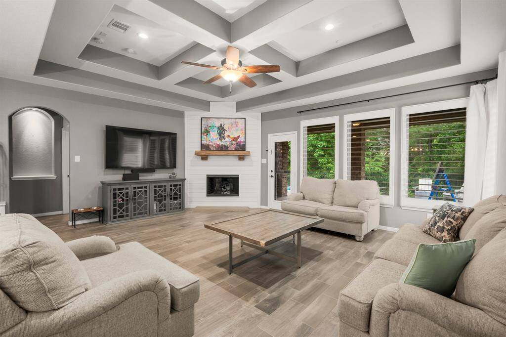 The inviting family room offers a serene retreat, with four bright windows boasting plantation shutters, framing views of the private backyard and covered porch. A rear door with French window provides seamless access, making outdoor entertaining effortless.
