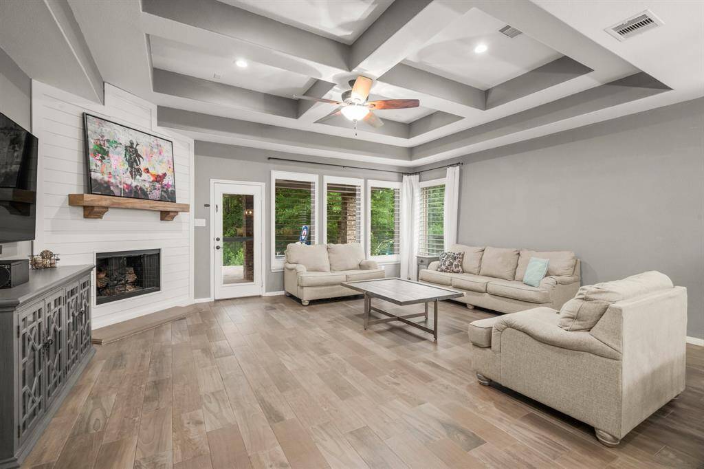 The heart of this living room is the impressive gaslog fireplace with shiplap surround, topped with a stately wood mantle. A wall of windows fills the space with abundant natural light, while the rich wood-look tile flooring adds a touch of sophistication and elegance. For an in-depth look, explore our online documents or click the movie reel icon to view a walk-through video of this stunning space.