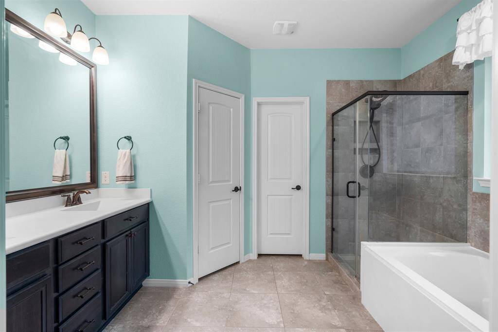 The double vanities boast solid surface countertops and integrated sinks. The large walk-in closet offers built-in shelving and ample hanging space.