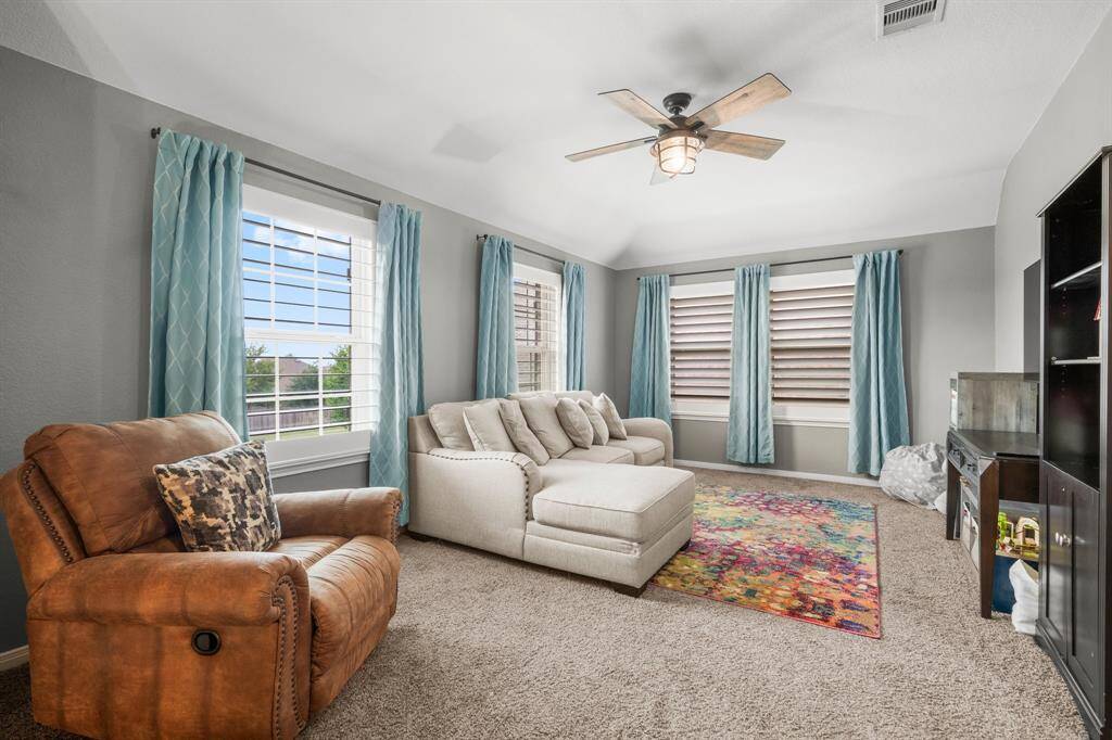 This spacious game room is designed for both fun and relaxation, complete with a convenient hallway closet for extra storage. Whether you're hosting game night, enjoying a movie marathon, or simply unwinding, this inviting space delivers. Highlights include plush carpeting, a charming sloped ceiling, four sunlit windows across two walls, and a stylish lighted ceiling fan for added comfort and ambiance.
