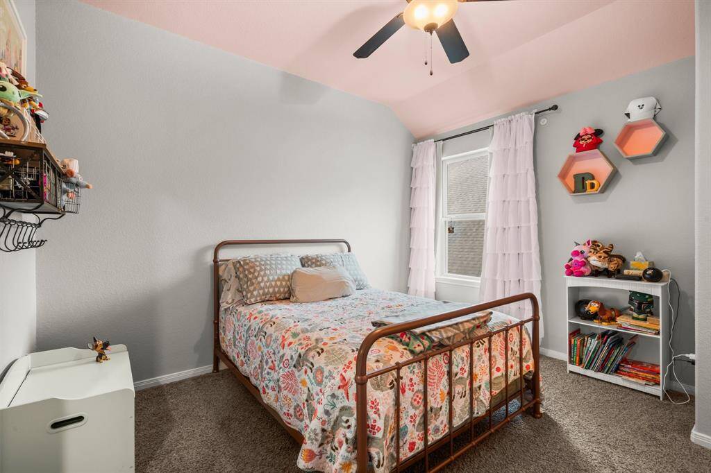 This secondary bedroom offers privacy from the other upstairs rooms, making it an ideal guest suite with its own private full bathroom. Highlights include plush carpeting, a sloped ceiling, a spacious walk-in closet, a large sunlit window, and a lighted ceiling fan.
