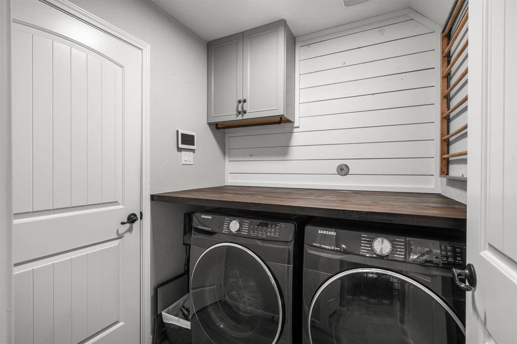 Functional Laundry Room has a built-in cabinet for storage, shiplap wood accent wall, and folding counter. Please exclude washer and dryer.